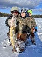 River Brooks Fedorka, age 4, pulls a chain pickerel through the ice in Shohola, with minimal assistance from his dad John, and with encouragement from 5-year-old brother Roman Wade.