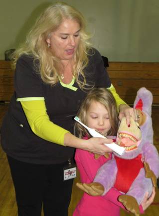 During this first grade assembly, first grader Chloe Longhenry (pictured holding Amato's purple dental patient) assisted as Amato showed the class how to properly brush teeth.
