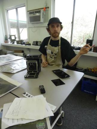 Photography Fellow Kevin Bond sits with his antique speed graphic 4x5 camera to the other one near the door.