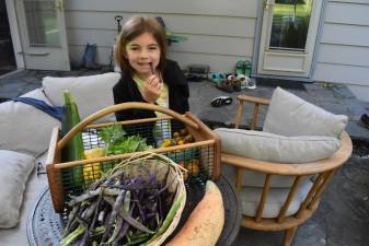 Juno, 8, samples the garden haul before school on Aug. 27.