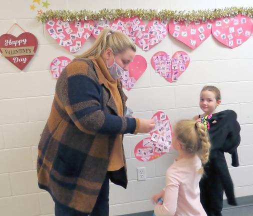 Miss Katelyn Jeleniewicz helps her students hang up their Valentines (Photo by Peg Snure)