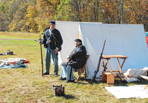 Civil War soldiers hang outside their tents.