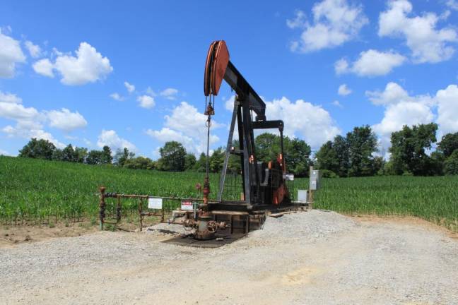 An old oil well in a corn field.