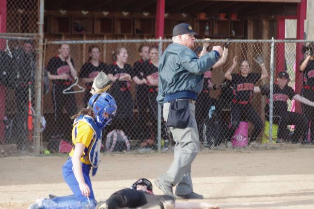 The umpire gives the out signal after a play at home plate.