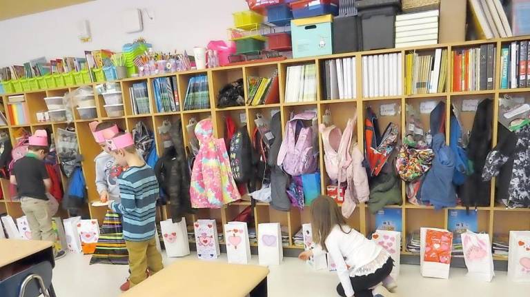 Students In Mrs. Lawson’s kindergarten class dropping their Valentines into their classmates’ bags (Photo by Peg Snure)